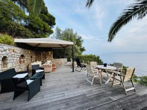a wooden deck with chairs and tables and an umbrella at Villa Bienvenue Apartments in Kanapitsa