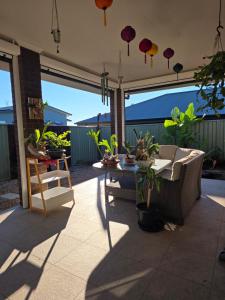 a patio with a table and chairs and potted plants at Quiet Homestay Ulladulla in Ulladulla