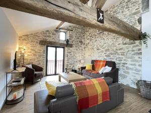 a living room filled with furniture and a stone wall at Le gîte d'etxerria in Arhansus