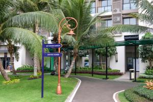 a street sign in front of a building with palm trees at Arka by TwoSpaces Studio @Skyhouse Apartment in Cilenggang