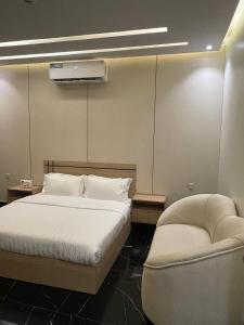 a bedroom with a white bed and a chair at فلل اسوار الوسام الفندقية in Taif +21 photos