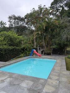 a swimming pool with a slide and a playground at Casa de campo em meio a natureza in Araras Petropolis