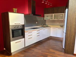 a kitchen with white cabinets and a red wall at Dúplex centro de Ribeira con WIFI by Cristian&Tamara"alquileres" in Ribeira