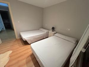 two beds in a small room with wooden floors at Dúplex centro de Ribeira con WIFI by Cristian&Tamara"alquileres" in Ribeira +3 photos