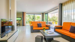 a living room with orange furniture and a television at Villa Bahamas - Jacuzzi e piscina aquecível em Armação de Pêra in Armação de Pêra +42 photos