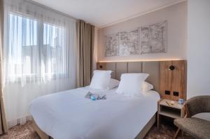 a bedroom with a large white bed and a window at The Originals city, Hôtel Harys in Vichy