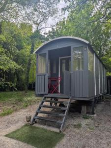 a gray tiny house with a red chair in it at Roulotte enchantée in Cornillé-les-Caves