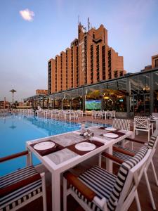 a restaurant with a table and chairs next to a pool at Babylon Rotana Hotel in Baghdād