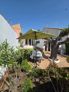 a patio with a table and a green umbrella at Maison Valras Plage très bon emplacement in Valras-Plage