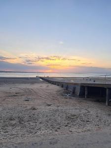 a pier on the beach with a sunset in the background at The Pilgrims Cove in Burnham on Sea