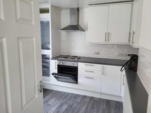 a kitchen with white cabinets and a stove at The Pilgrims Cove in Burnham on Sea