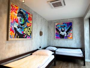 a bedroom with two beds and paintings on the wall at Vila CampoAmor Pasohlávky in Pasohlávky