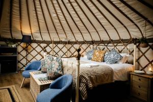 a bedroom with a bed and two chairs in a yurt at Kelburn Yurts - Bourtrees in Fairlie