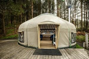 a canvas tent with a table in it on a deck at Kelburn Yurts - Bourtrees in Fairlie