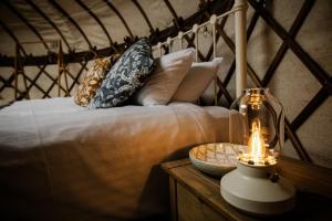 a bed with pillows and a lamp on a table at Kelburn Yurts - Bourtrees in Fairlie +24 photos