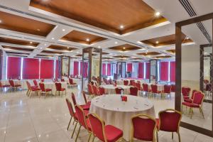 a banquet hall with white tables and red chairs at Avari Xpress Gulberg in Lahore