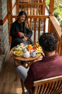 a man and a woman sitting at a table with food at 8fold by Larisa, Jibhi in Jibhi