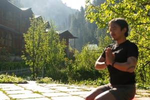 a man sitting on the ground in a garden at 8fold by Larisa, Jibhi in Jibhi +67 photos
