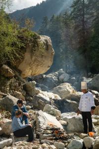 a group of people sitting on rocks near a river at 8fold by Larisa, Jibhi in Jibhi