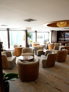 a waiting room with couches and tables and windows at Babylon Rotana Hotel in Baghdād