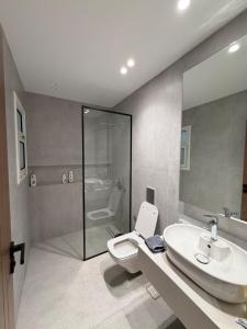 a bathroom with a toilet and a sink and a shower at Chic Stays Modern 3BR in Mountain View ICITY in 6th Of October +16 photos