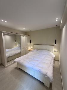 a bedroom with a large white bed and a mirror at Chic Stays Modern 3BR in Mountain View ICITY in 6th Of October