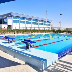 a large swimming pool in front of a building at Chic Stays Modern 3BR in Mountain View ICITY in 6th Of October