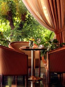 a table in a restaurant with two chairs and a window at Savoy Hotel in Piraeus