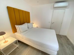 a bedroom with a white bed and a wooden headboard at Vibrant Setúbal II, By Home Match in Setúbal