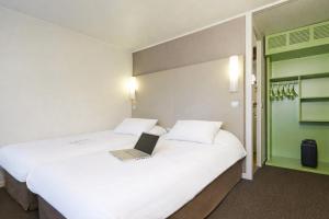 a hotel room with two beds with a laptop on them at Campanile Lens in Lens +21 photos