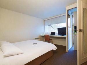 a bedroom with a bed and a desk with a computer at Campanile Lens in Lens