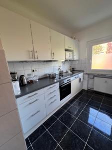 a kitchen with white cabinets and a black tile floor at City Quartier Wedel in Wedel