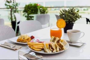 a table with two plates of food and a glass of orange juice at The Westerly Riverside Hotel in Phnom Penh