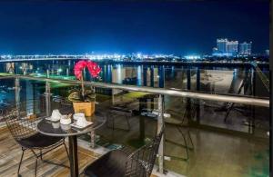 a table and chairs on a balcony at night at The Westerly Riverside Hotel in Phnom Penh