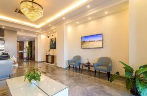 a living room with chairs and a tv on the wall at The Westerly Riverside Hotel in Phnom Penh