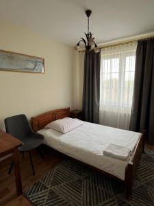 a bedroom with a bed and a desk and a window at Hotel Lanckorona in Jędrzejów