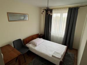 a small bedroom with a bed and a desk and a window at Hotel Lanckorona in Jędrzejów