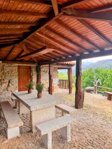 a picnic table and benches under a wooden roof at Casa do Monte Sereno in Celorico de Basto