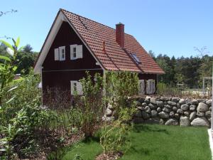 ein schwarzes Haus mit rotem Dach und einer Steinmauer in der Unterkunft Küstenhaus Koserow in Ostseebad Koserow