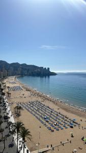 a beach with many umbrellas and people on it at Apartamento Benidorm primera linea in Benidorm