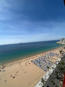 a beach with many umbrellas and people on it at Apartamento Benidorm primera linea in Benidorm