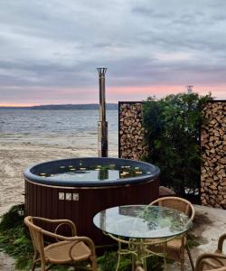 a hot tub on the beach with a table and chairs at Secret River Rooms in Pereiaslav-Khmelnytskyi