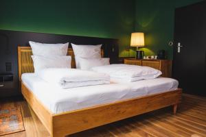 a large bed with white pillows and a green wall at friedrich DAS BETT in Braunschweig +5 photos