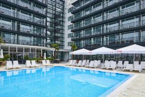 a swimming pool with chairs and umbrellas in front of a building at Hotel Bavaro in Sunny Beach