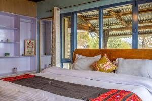 a bedroom with a bed with a large window at Vibe Hostel Naddi - Near Dal Lake in Dharamshala