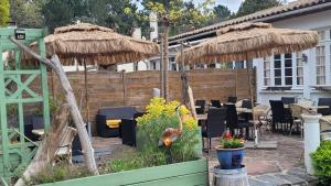 a patio with tables and chairs and umbrellas at Résidence Fleur des Pins - Gites & Chambres d'Hôtes in Saint-Georges-dʼOléron