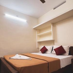 a bedroom with a bed with red and white pillows at AMAN Residency in Kallar Vattiyar