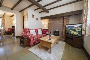 a living room with a red couch and a tv at Lyke Wake Cottage in Northallerton