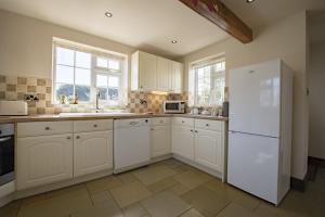 a kitchen with white cabinets and a white refrigerator at Lyke Wake Cottage in Northallerton