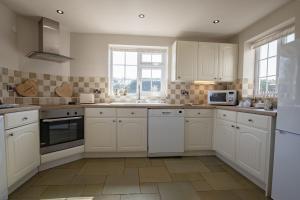 a white kitchen with white cabinets and a microwave at Lyke Wake Cottage in Northallerton +28 photos